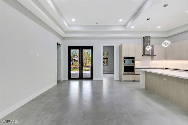 3366 72nd Ave NE, Naples, FL 34120 - kitchen with modern cabinets, a tray ceiling, wall chimney exhaust hood, light countertops, and finished concrete flooring