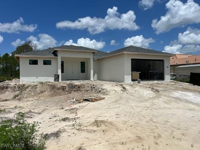 1005 State Ave, Lehigh Acres, FL 33972 - prairie-style home featuring an attached garage and stucco siding