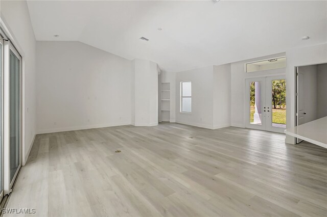 3390 12th Ave SE, Naples, FL 34117 - unfurnished living room featuring french doors, light wood-style flooring, lofted ceiling, and baseboards