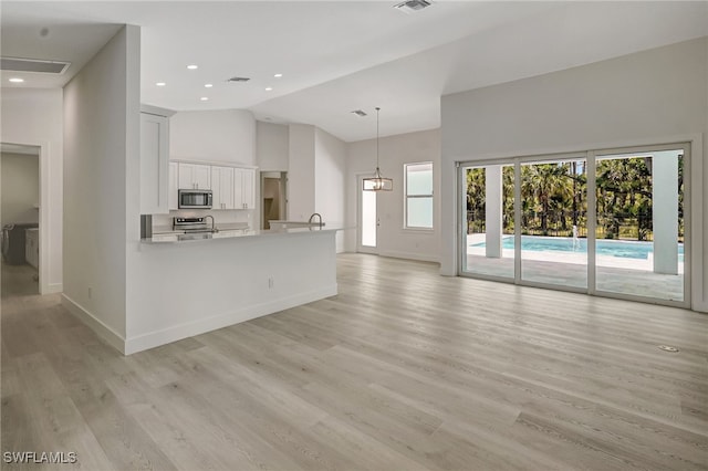 3390 12th Ave SE, Naples, FL 34117 - unfurnished living room featuring high vaulted ceiling, baseboards, light wood-style flooring, and recessed lighting