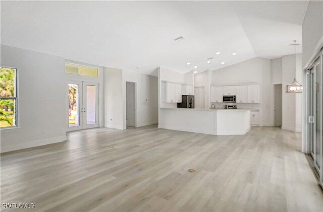 3390 12th Ave SE, Naples, FL 34117 - unfurnished living room with high vaulted ceiling, light wood-style floors, baseboards, and french doors