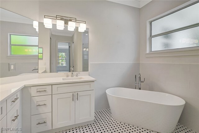 3390 12th Ave SE, Naples, FL 34117 - bathroom with tile walls, vanity, a soaking tub, and a wainscoted wall