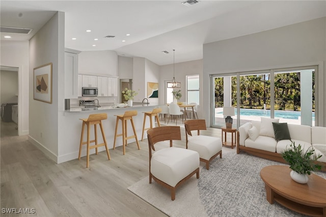 3390 12th Ave SE, Naples, FL 34117 - living room featuring light wood-style floors, high vaulted ceiling, baseboards, and recessed lighting