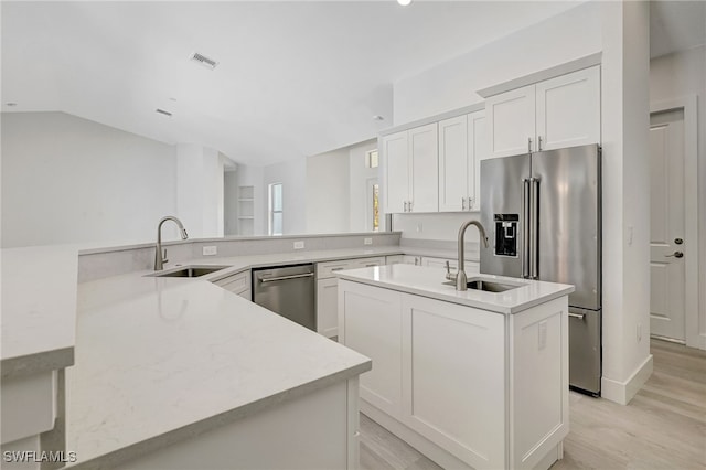 3390 12th Ave SE, Naples, FL 34117 - kitchen with stainless steel appliances, a sink, an island with sink, light wood finished floors, and vaulted ceiling
