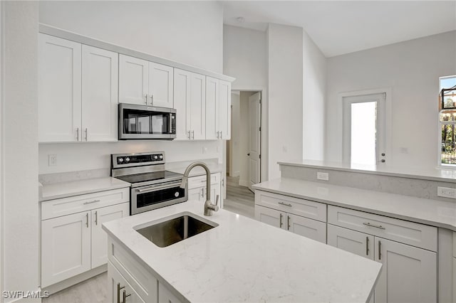 3390 12th Ave SE, Naples, FL 34117 - kitchen featuring appliances with stainless steel finishes, a sink, light wood-type flooring, white cabinets, and light stone counters