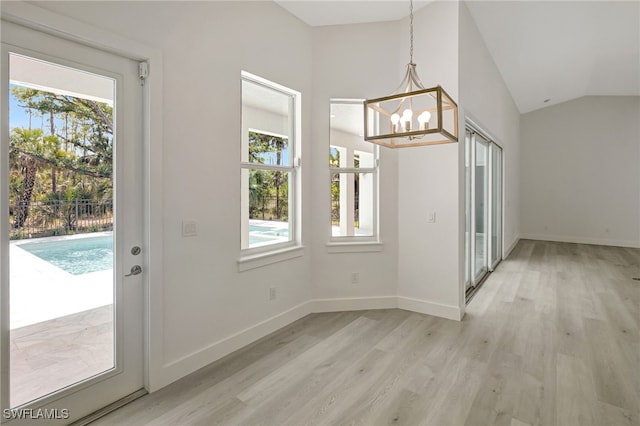 3390 12th Ave SE, Naples, FL 34117 - unfurnished dining area featuring a chandelier, light wood-style flooring, lofted ceiling, and baseboards