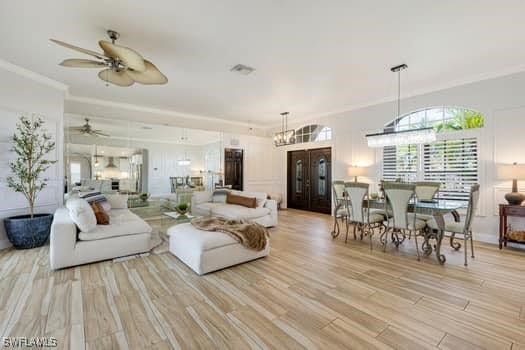 914 Albert Ave, Lehigh Acres, FL 33971 - living room featuring a ceiling fan, crown molding, light wood-style flooring, and a chandelier