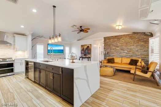 914 Albert Ave, Lehigh Acres, FL 33971 - kitchen featuring stainless steel appliances, wall chimney range hood, open floor plan, light countertops, and light wood-style flooring