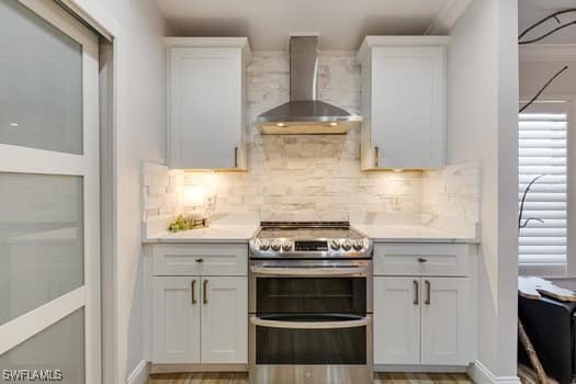 914 Albert Ave, Lehigh Acres, FL 33971 - kitchen with double oven range, wall chimney range hood, light countertops, and tasteful backsplash