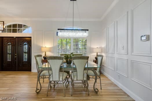914 Albert Ave, Lehigh Acres, FL 33971 - dining room featuring a chandelier, ornamental molding, light wood-style flooring, and a decorative wall