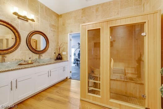 914 Albert Ave, Lehigh Acres, FL 33971 - bathroom featuring wood finished floors, double vanity, and backsplash