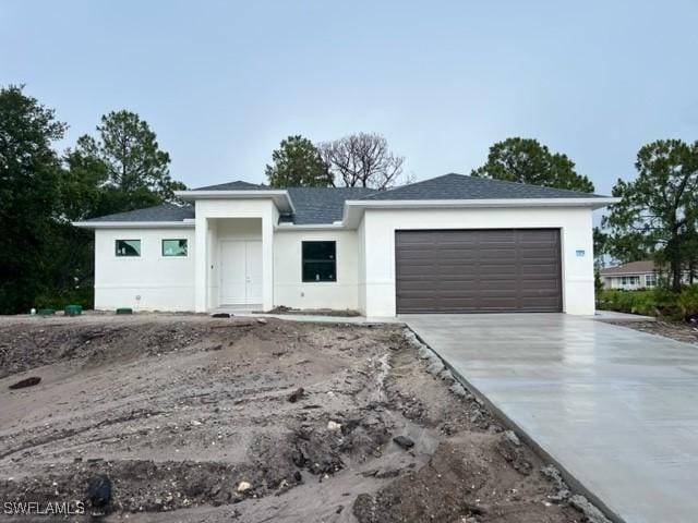 3604 Flora Ave N, Lehigh Acres, FL 33971 - view of front of house with a garage, concrete driveway, stucco siding, and a shingled roof