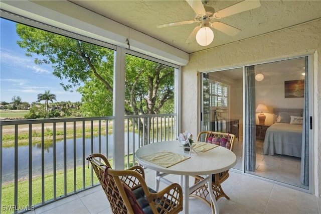 sunroom featuring a water view and ceiling fan