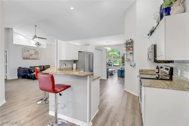 120 Heritage Way, Naples, FL 34110 - kitchen featuring appliances with stainless steel finishes, a breakfast bar area, backsplash, light wood-style flooring, and lofted ceiling