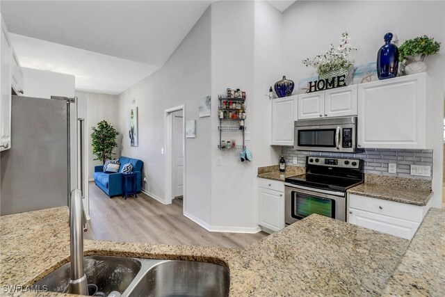 120 Heritage Way, Naples, FL 34110 - kitchen with appliances with stainless steel finishes, light wood-type flooring, tasteful backsplash, baseboards, and white cabinetry