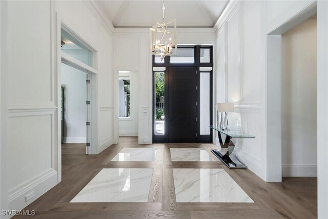 541 Whispering Pine Ct, Naples, FL 34103 - entryway featuring a chandelier, a decorative wall, baseboards, wood finished floors, and vaulted ceiling