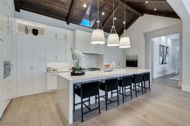 541 Whispering Pine Ct, Naples, FL 34103 - kitchen with wooden ceiling, light wood-type flooring, oven, a spacious island, and decorative backsplash