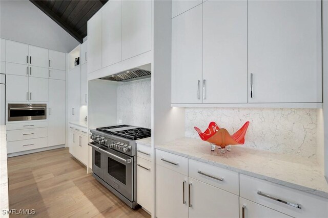 541 Whispering Pine Ct, Naples, FL 34103 - kitchen featuring appliances with stainless steel finishes, light wood-type flooring, white cabinetry, light stone countertops, and backsplash