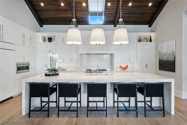 541 Whispering Pine Ct, Naples, FL 34103 - kitchen featuring wood ceiling, stainless steel oven, white cabinets, a large island, and tasteful backsplash