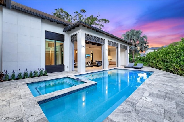 541 Whispering Pine Ct, Naples, FL 34103 - pool at dusk with a patio area, a pool with connected hot tub, and an outdoor hangout area