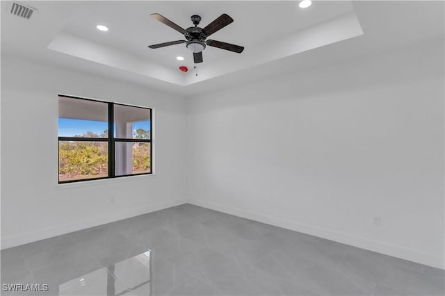 spare room with a tray ceiling, recessed lighting, baseboards, and a ceiling fan