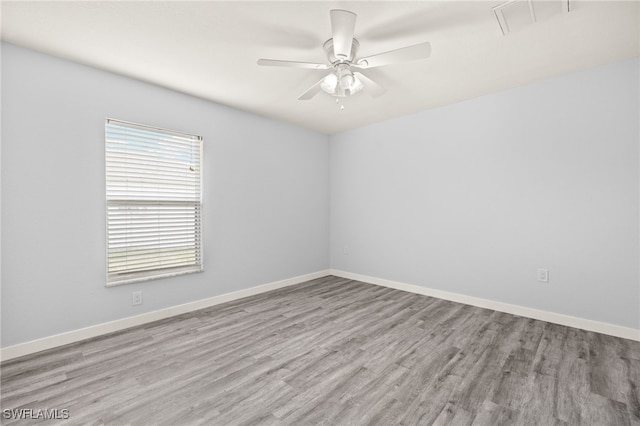 spare room with wood finished floors, a ceiling fan, and baseboards