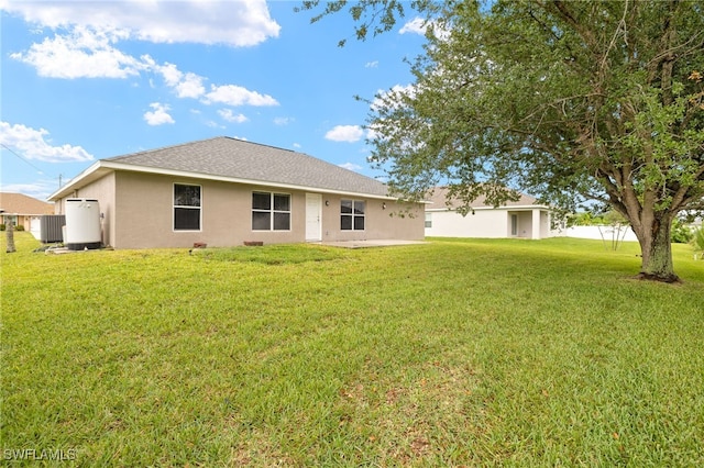 back of house with a yard, stucco siding, and central air condition unit