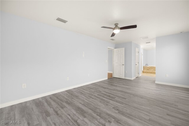 unfurnished room featuring wood finished floors, ceiling fan, and baseboards