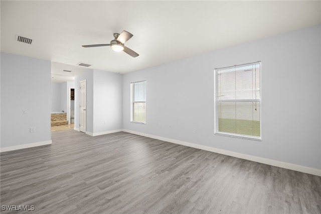 empty room featuring wood finished floors, baseboards, and ceiling fan