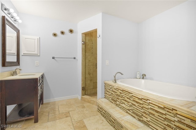 bathroom with a garden tub, vanity, stone tile flooring, a stall shower, and baseboards