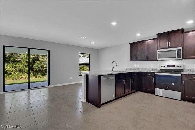 23206 Fitzpatrick Ave, Port Charlotte, FL 33980 - kitchen with stainless steel appliances, a sink, a peninsula, recessed lighting, and light stone counters
