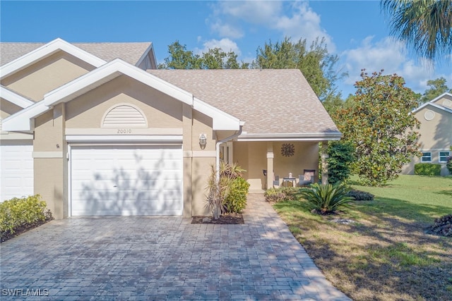 20010 Wolfel Trl, Estero, FL 33928 - view of front of property featuring stucco siding, decorative driveway, a garage, a front lawn, and roof with shingles