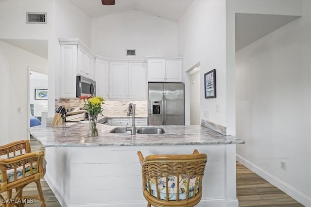 950 Moody Rd Unit 111, North Fort Myers, FL 33903 - kitchen with stainless steel appliances, a sink, high vaulted ceiling, a peninsula, and light stone countertops