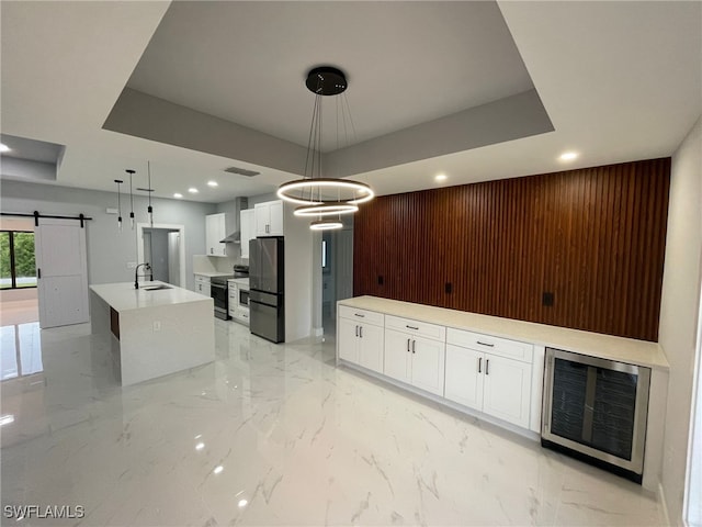 kitchen featuring appliances with stainless steel finishes, a barn door, a spacious island, light marble finish flooring, and recessed lighting