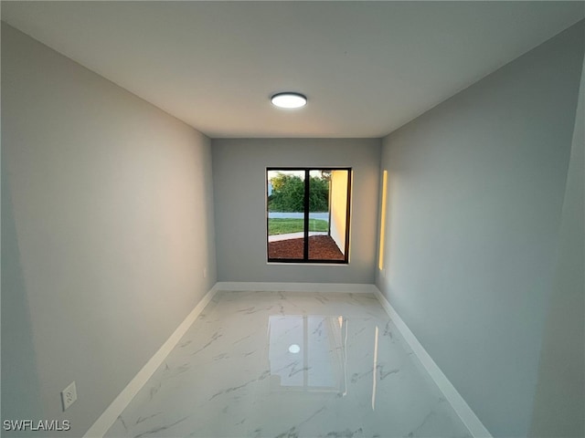 unfurnished room featuring light marble finish floors and baseboards
