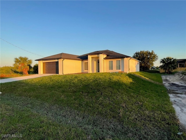 view of front of home featuring stucco siding, a garage, concrete driveway, and a front lawn