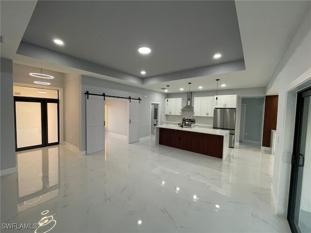 kitchen with freestanding refrigerator, baseboards, a tray ceiling, wall chimney exhaust hood, and recessed lighting