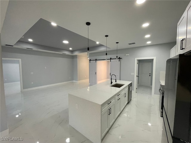 kitchen featuring a sink, a barn door, refrigerator, baseboards, and light marble finish flooring