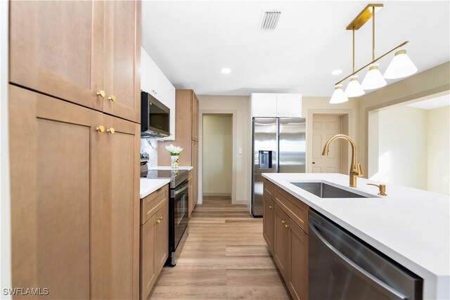 203 Carol Way, Fort Myers, FL 33905 - kitchen featuring appliances with stainless steel finishes, a sink, light wood finished floors, light countertops, and pendant lighting