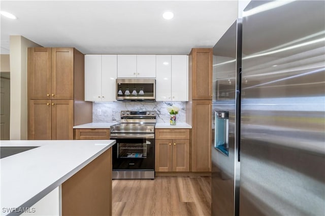 203 Carol Way, Fort Myers, FL 33905 - kitchen featuring stainless steel appliances, light wood-style flooring, light countertops, white cabinets, and brown cabinetry