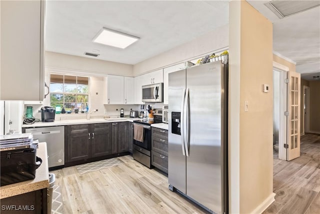 12206 Boat Shell Dr, Matlacha Isles, FL 33991 - kitchen featuring stainless steel appliances, light countertops, light wood-type flooring, and white cabinetry