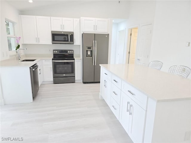 687 Grove Dr, Naples, FL 34120 - kitchen with stainless steel appliances, a sink, light wood-type flooring, white cabinetry, and recessed lighting