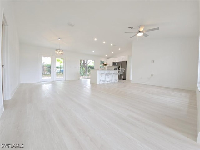 687 Grove Dr, Naples, FL 34120 - unfurnished living room with a chandelier, a ceiling fan, vaulted ceiling, light wood-style floors, and recessed lighting