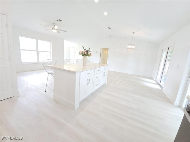 687 Grove Dr, Naples, FL 34120 - kitchen featuring light wood-style floors, a ceiling fan, white cabinets, a chandelier, and a center island