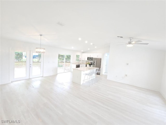 687 Grove Dr, Naples, FL 34120 - unfurnished living room featuring light wood-type flooring, lofted ceiling, a chandelier, a ceiling fan, and recessed lighting
