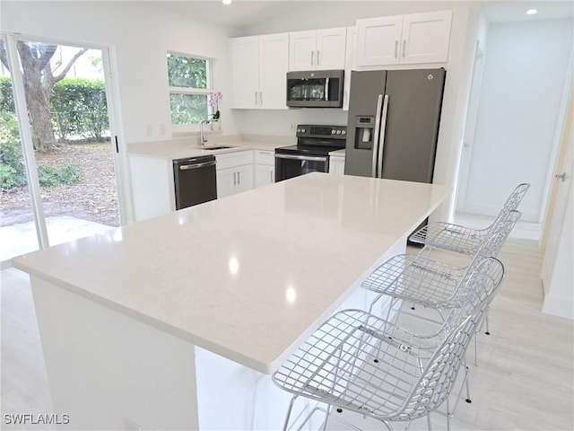 687 Grove Dr, Naples, FL 34120 - kitchen with stainless steel appliances, a sink, white cabinetry, a kitchen bar, and recessed lighting