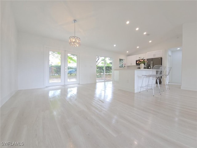 687 Grove Dr, Naples, FL 34120 - unfurnished living room with a chandelier, light wood-style flooring, recessed lighting, and lofted ceiling