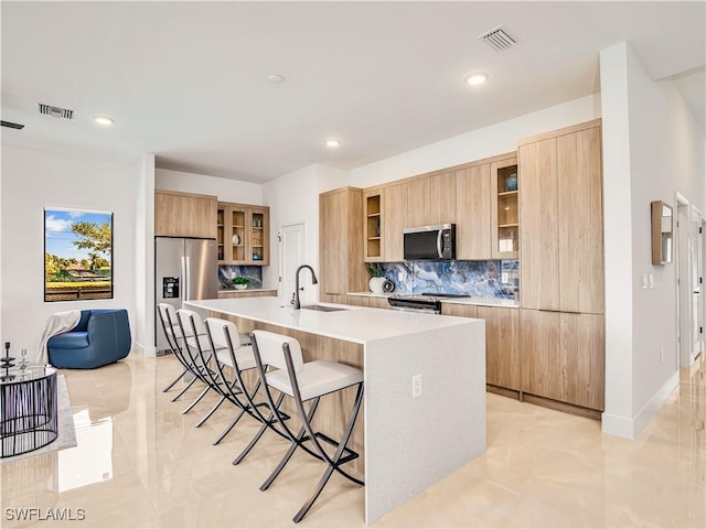 kitchen featuring appliances with stainless steel finishes, modern cabinets, a sink, a kitchen bar, and recessed lighting