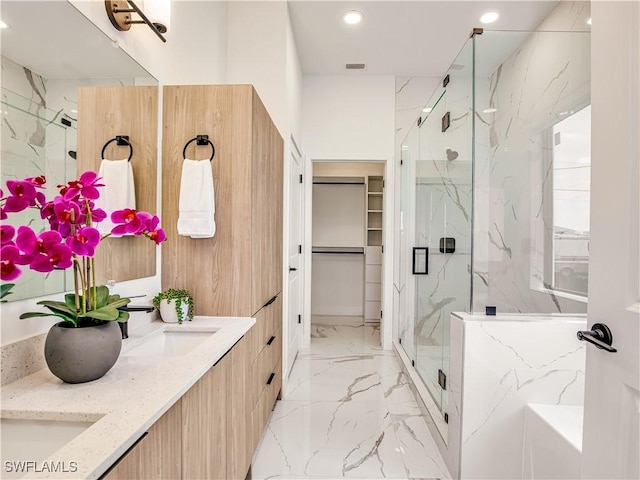 bathroom with marble tiled flooring, a marble finish shower, recessed lighting, a spacious closet, and double vanity