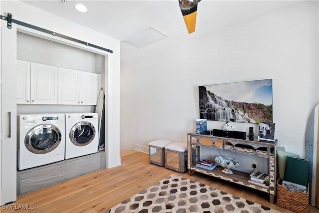 838 9th Ave S Unit 106, Naples, FL 34102 - clothes washing area with washing machine and clothes dryer, wood finished floors, a barn door, and cabinet space
